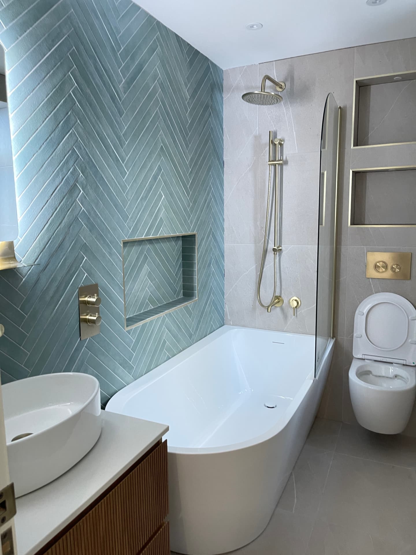 Freshly cleaned bathroom with blue herringbone tiles and freestanding bath